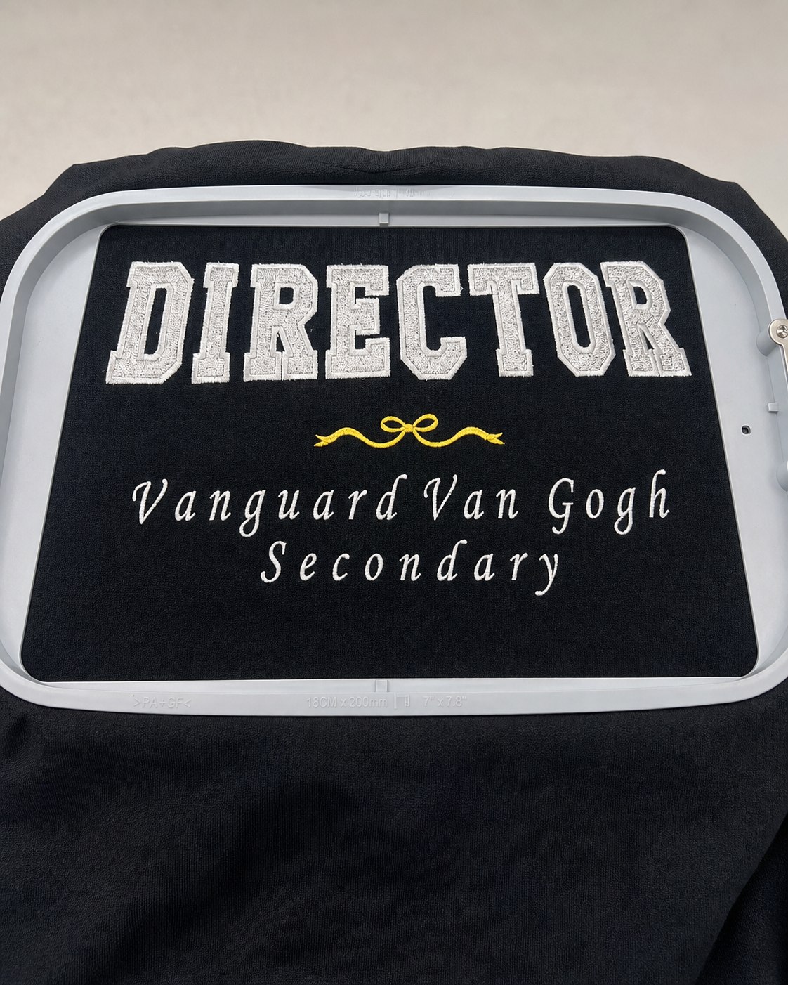 Silver Director vinyl fabric appliqué with white script on black fabric.